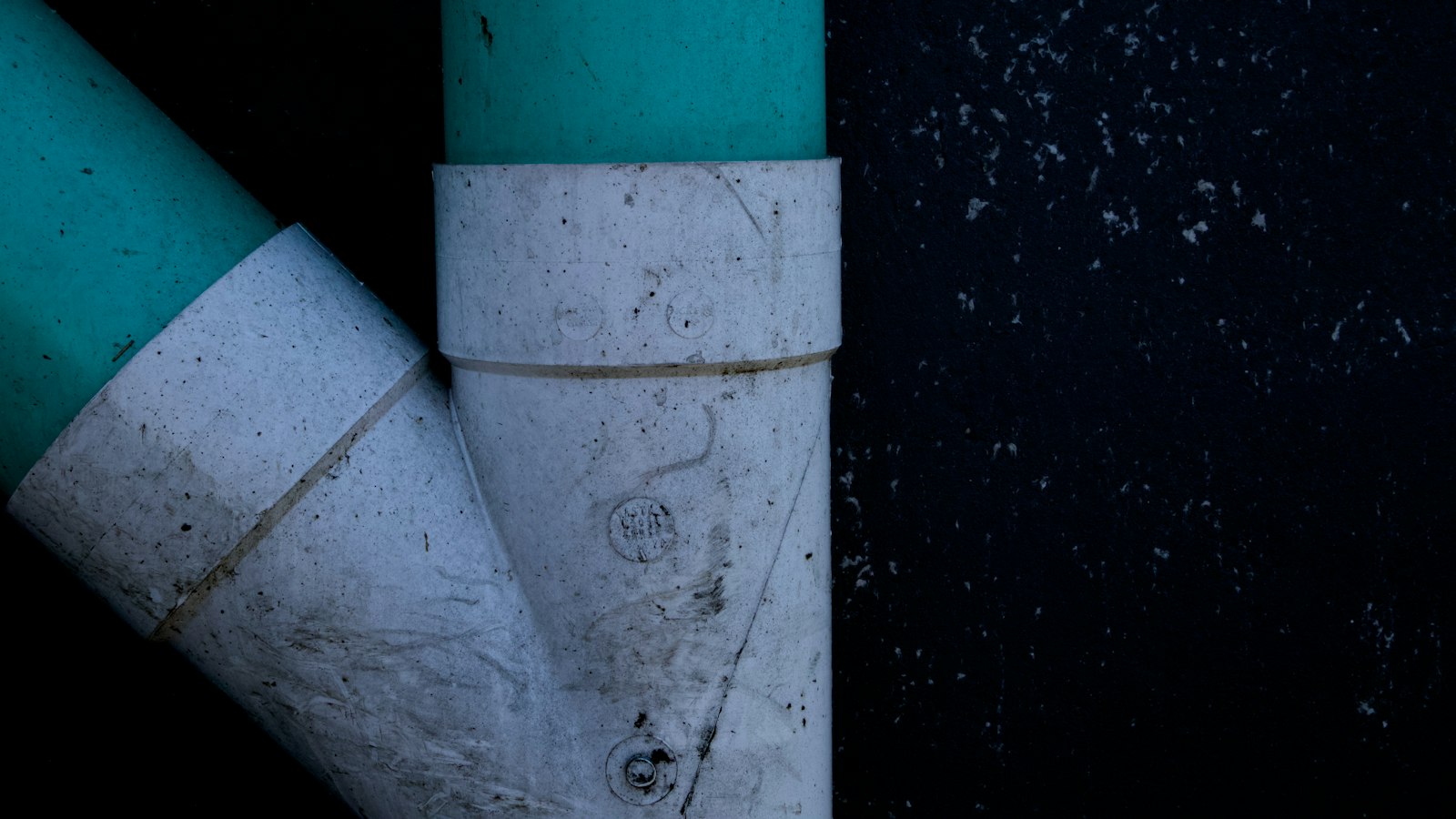 Green PVC sewer pipe joined at a white wye fitting, the kind of sewer lateral a sewer scope inspection camera travels through